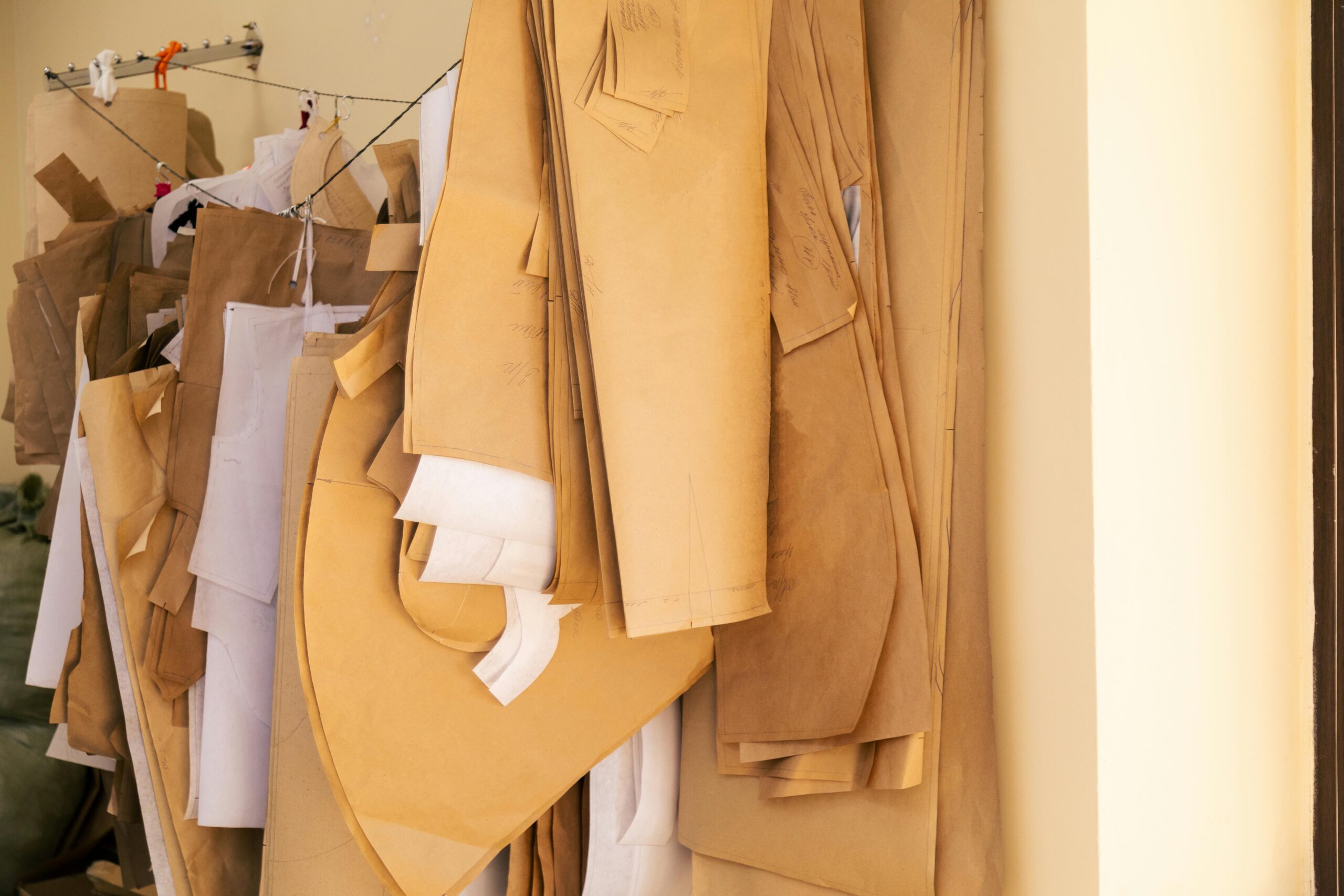 Close-up of sewing patterns hanging in a fashion design workshop, showcasing industry creativity.